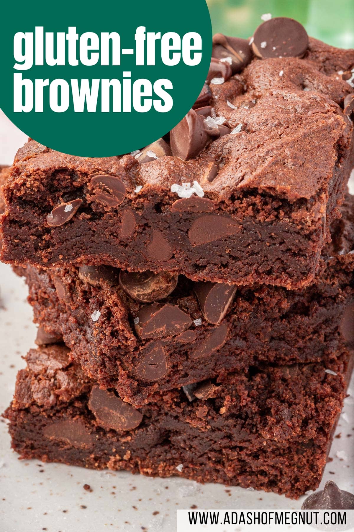 A stack of three gluten-free brownies on a small dessert plate topped with semi-sweet chocolate chips and flaky sea salt with a text overlay.