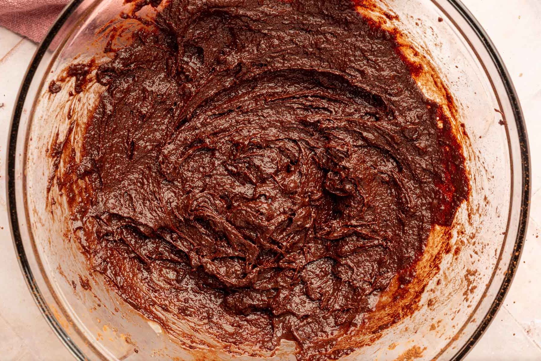 A glass mixing bowl of gluten-free brownie batter in it.