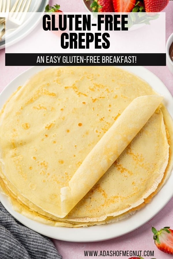 A stack of gluten-free crepes on a plate with the top one halfway rolled into a cyllinder.