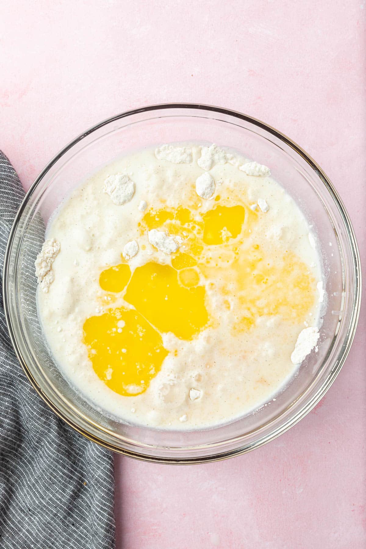 A glass mixing bowl with gluten-free flour, melted butter, water and milk before mixing together to make crepe batter.