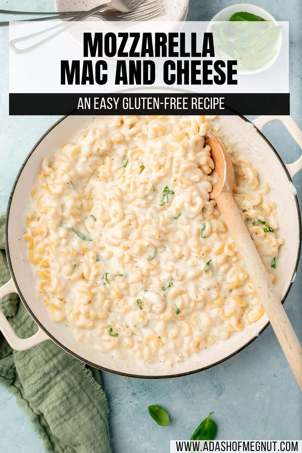 A large skillet of gluten-free mozzarella mac and cheese with a wooden spoon in it and a bowl of basil on the side.