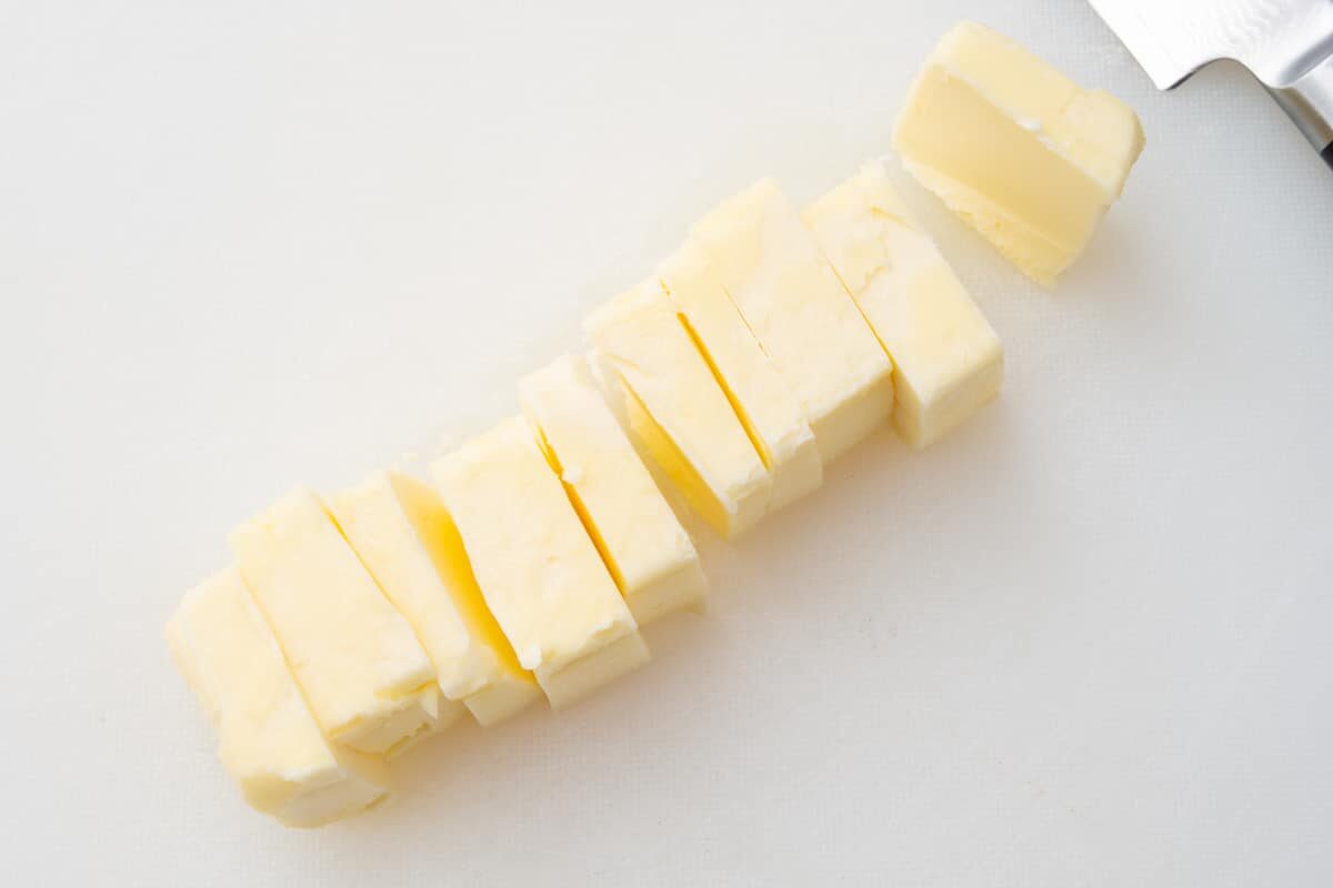 A stick of butter that has been cut into small tablespoon sized slices with a knife.