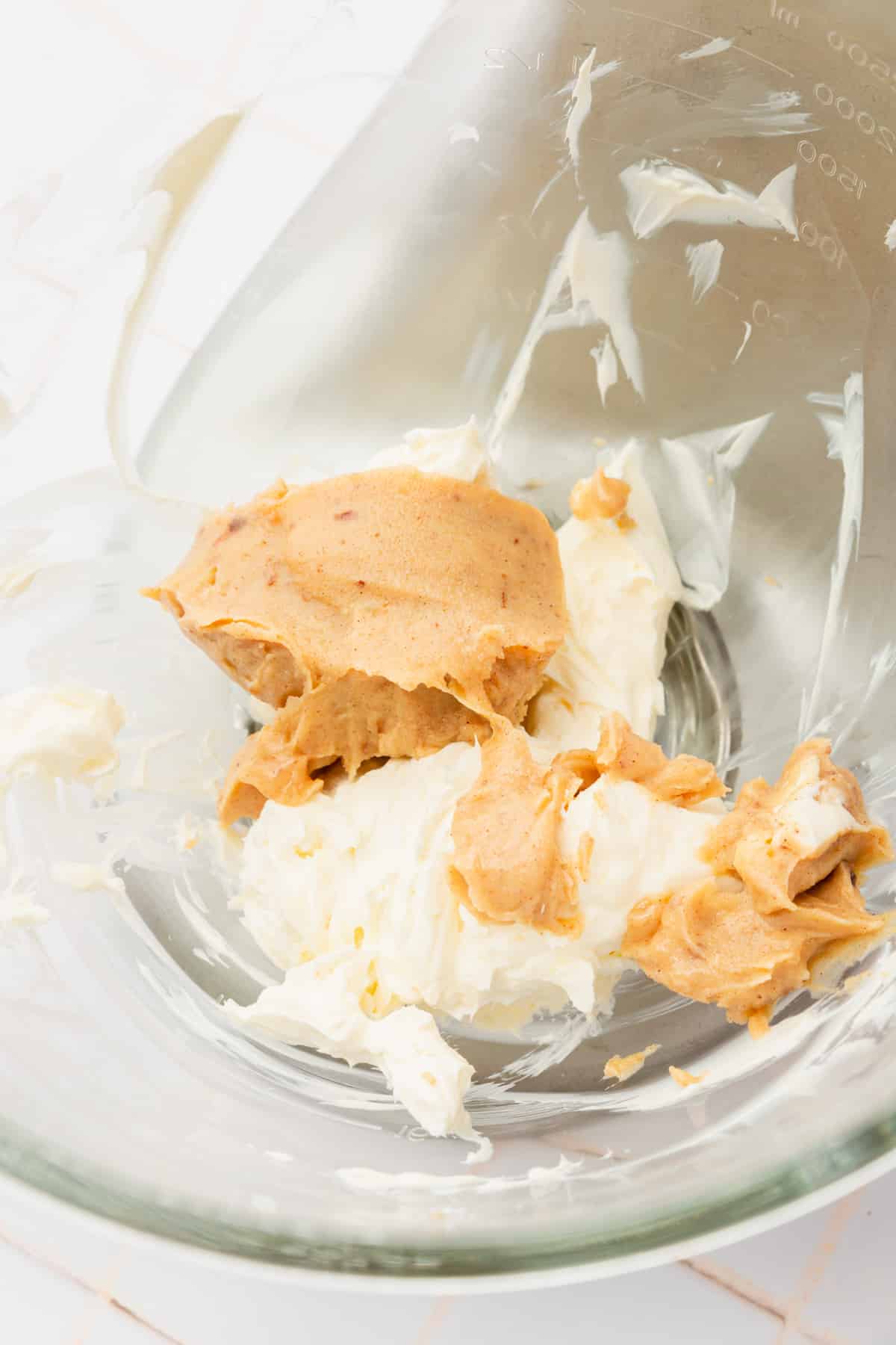 A glass mixing bowl with cream cheese and solidified browned butter in it.