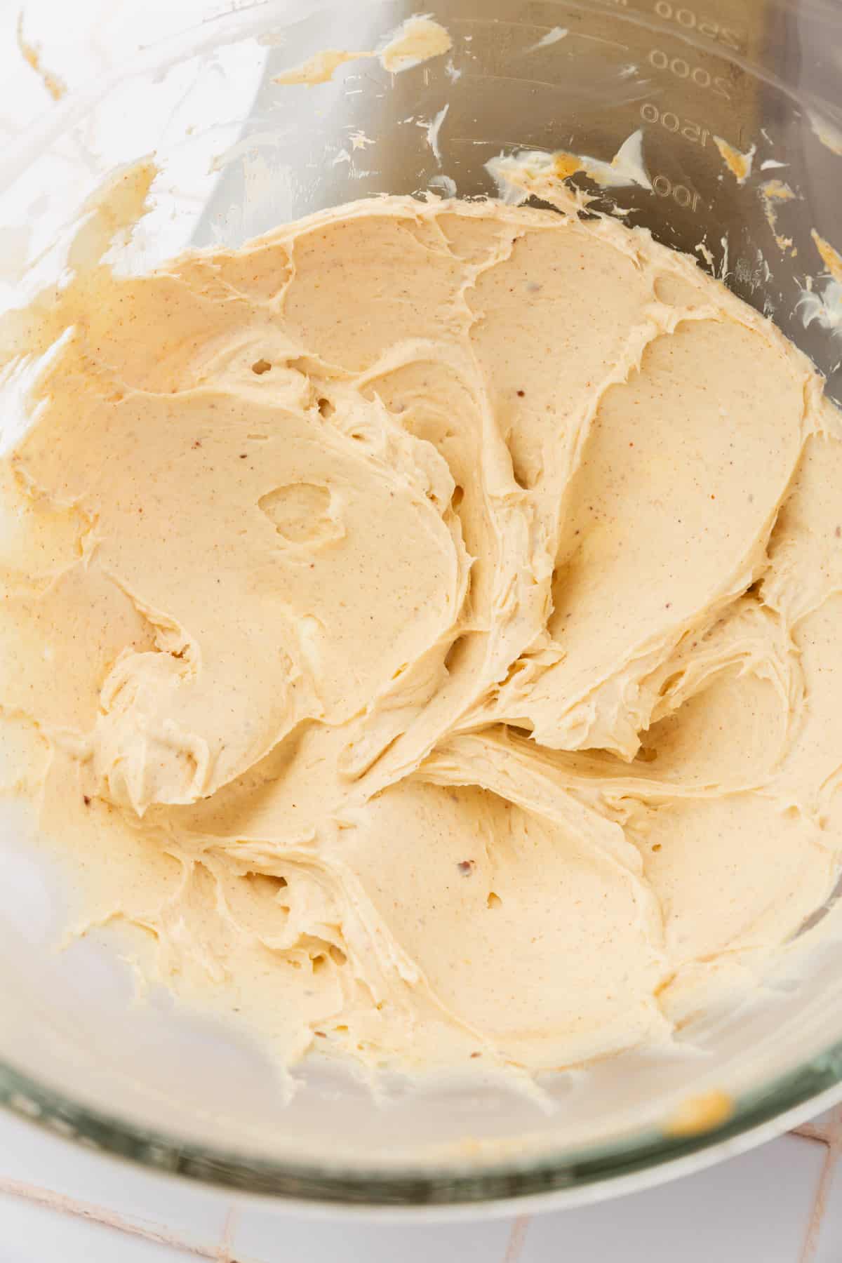 A glass mixing bowl with a brown butter cream cheese mixture in it.