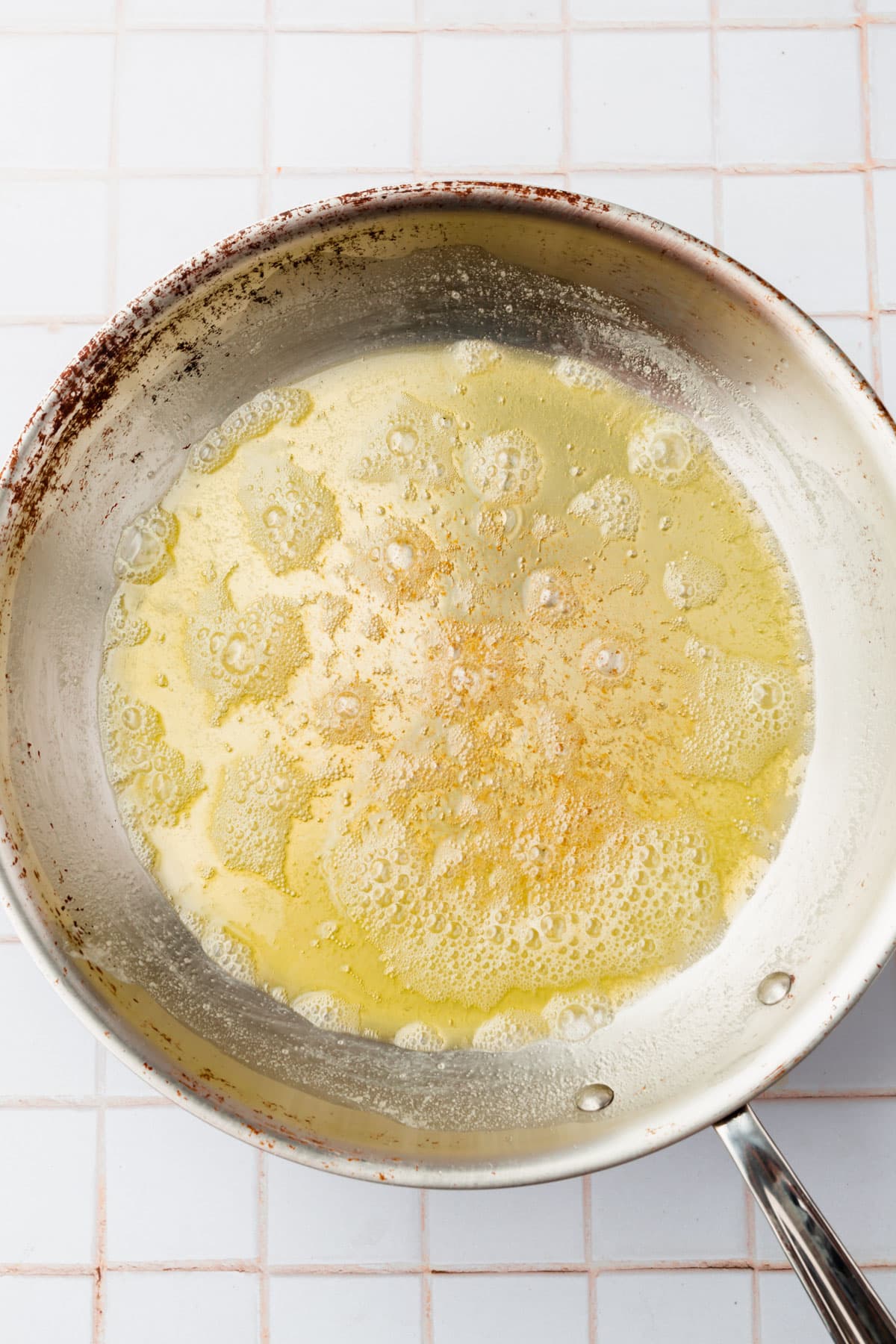 A stainless steel skillet with melted butter that is beginning to brown.