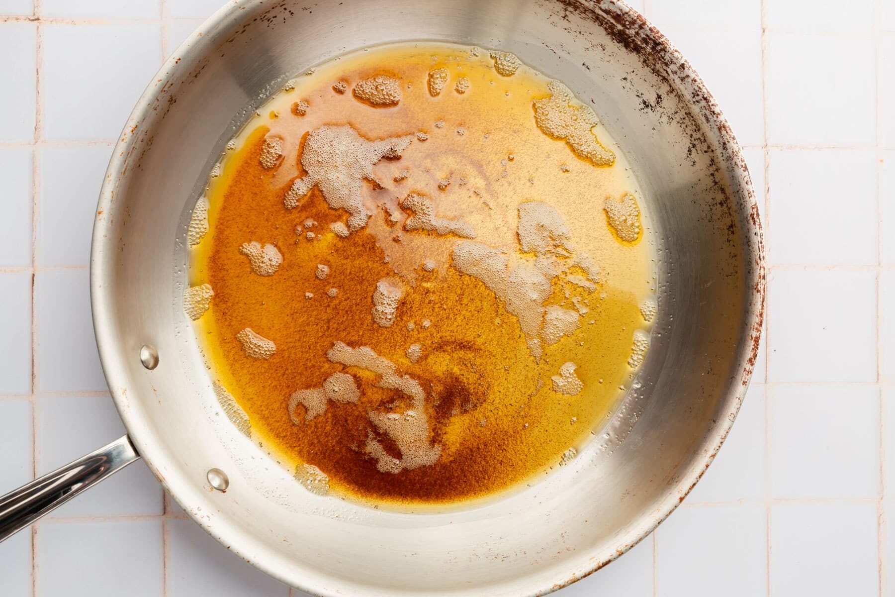 A stainless steel skillet with melted brown butter in it.