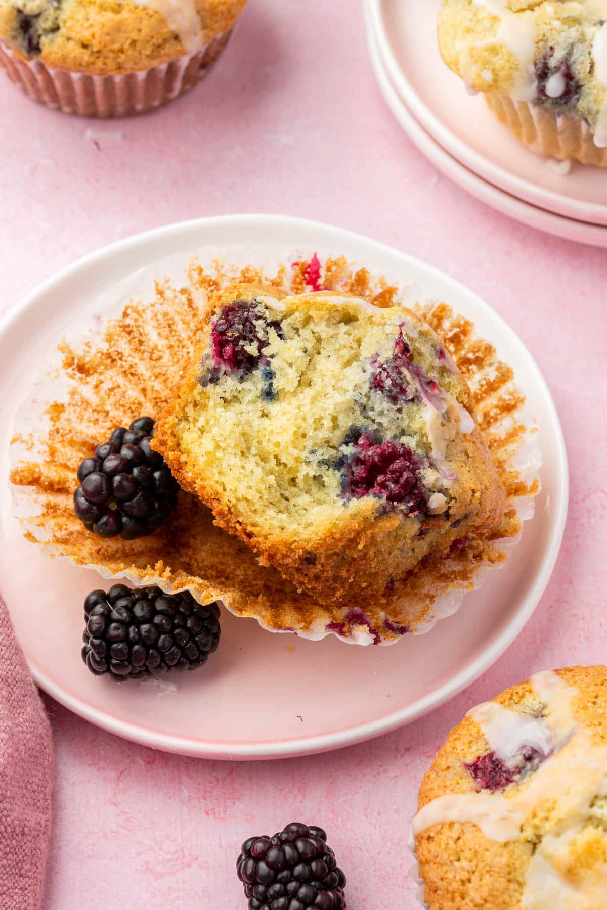 A gluten-free blackberry muffin on a dessert plate that has a bite taken out of it.