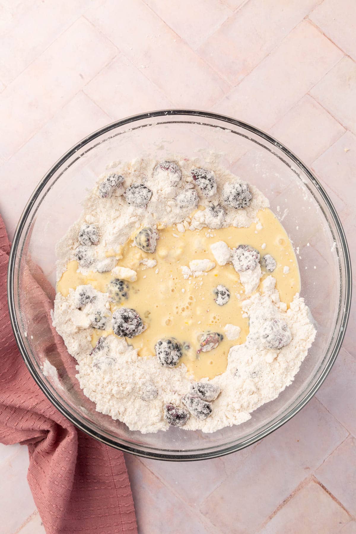 An overhead view of gluten-free flour mixed with fresh blackberries that has a buttermilk mixture poured over it.