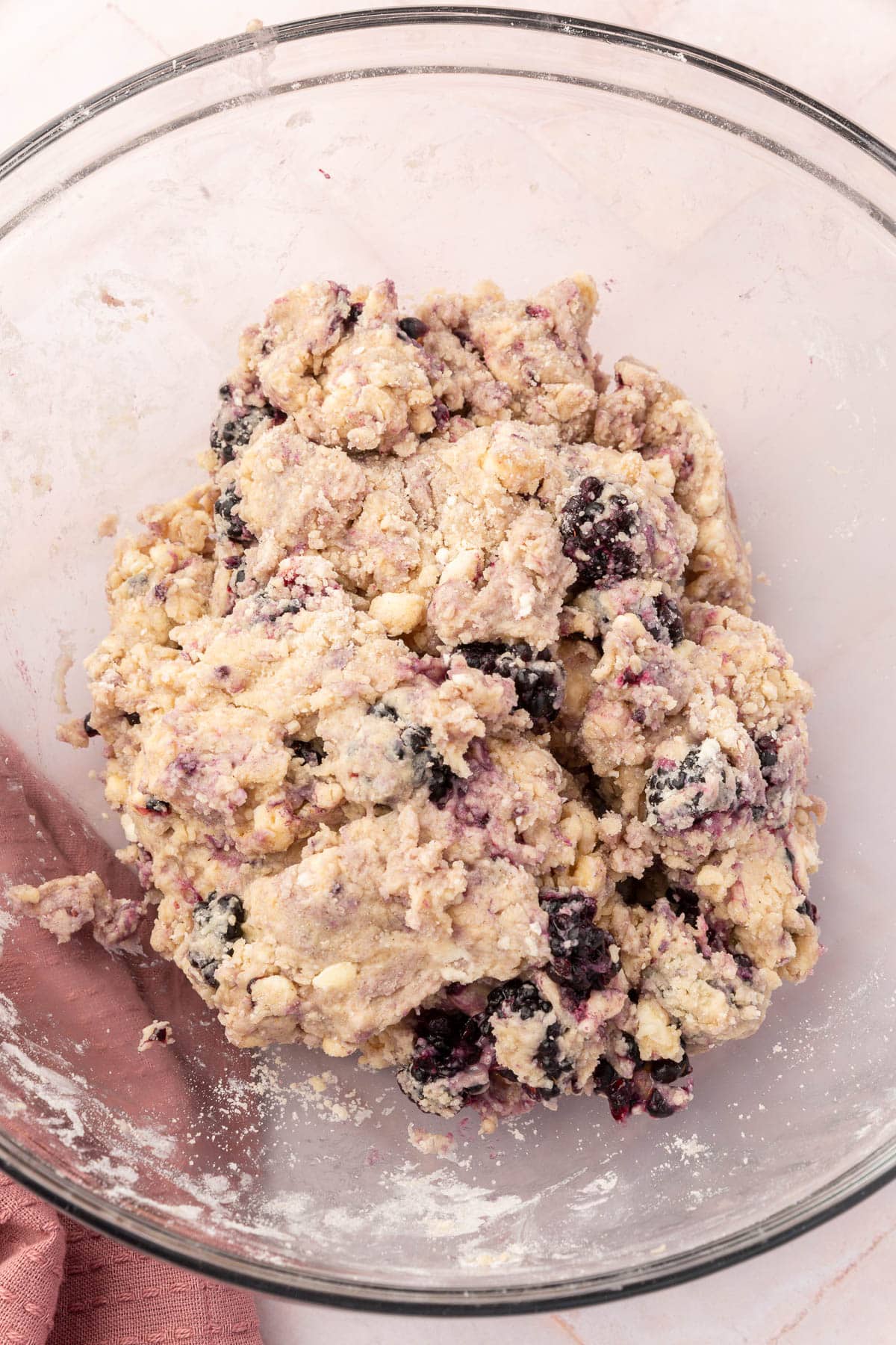 A glass mixing bowl filled with gluten-free blackberry scone dough.