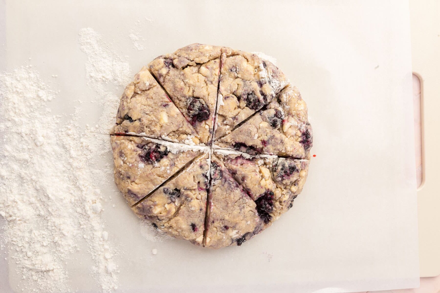 A round disk of gf blackberry scone dough cut into 8 wedges.