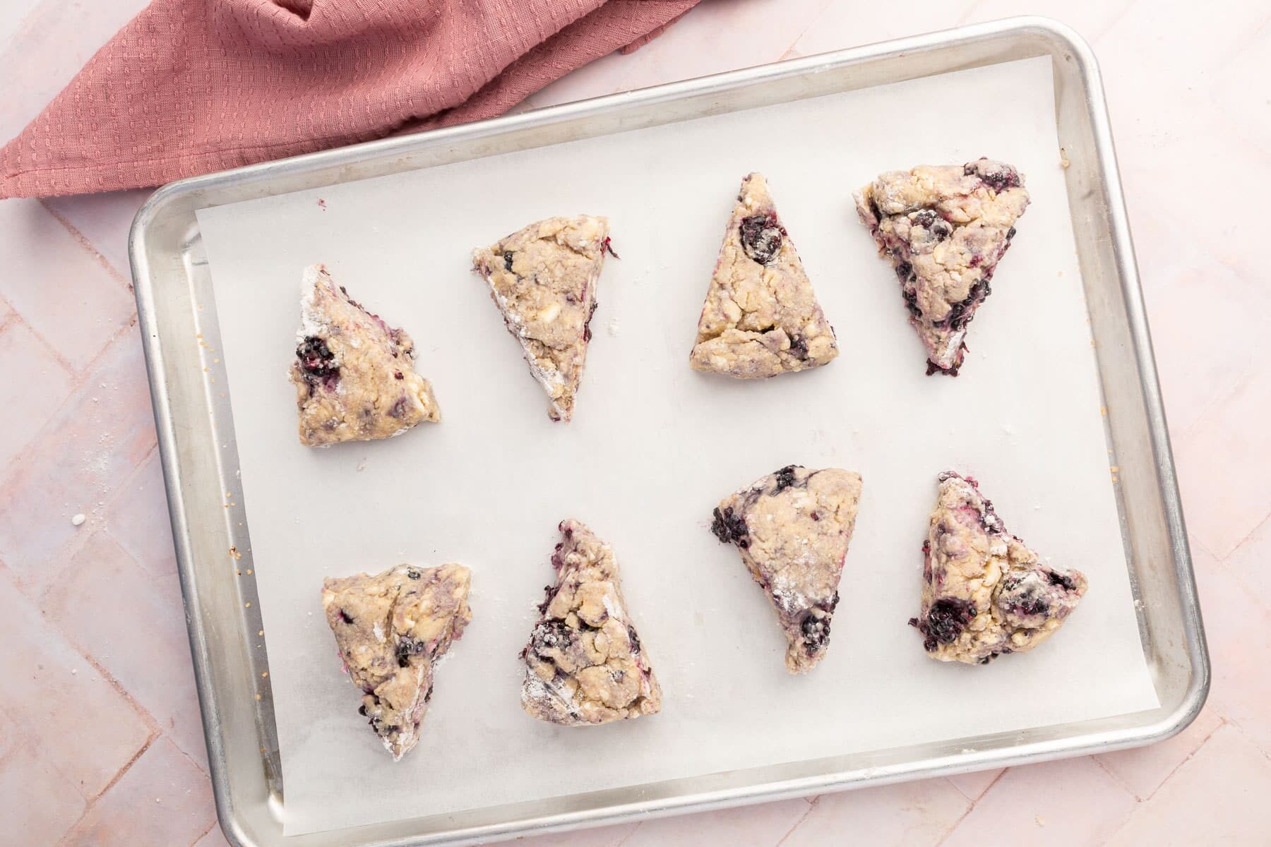 An overhead view of gf blackberry scone dough wedges on a baking sheet lined with parchment paper before baking in the oven.