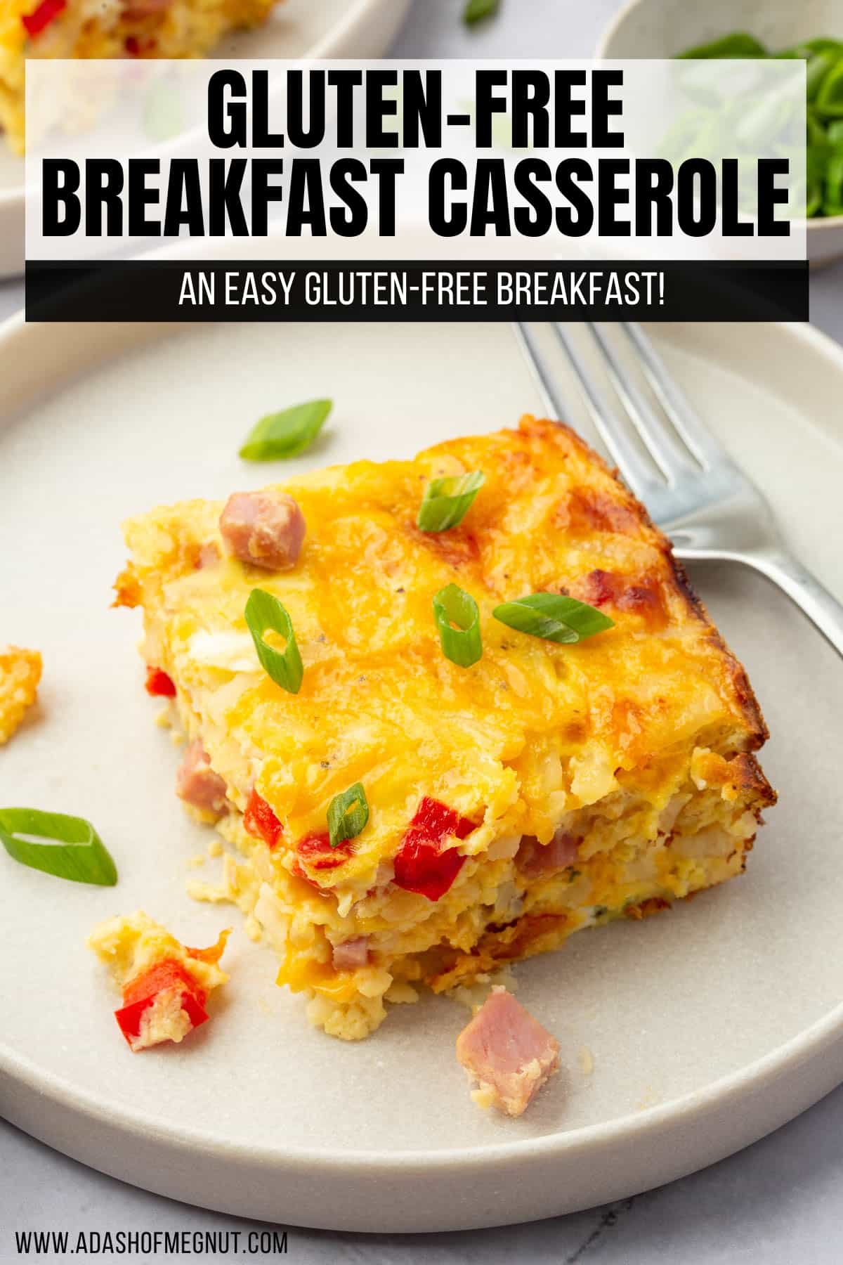 A single slice of ham egg and cheese casserole topped with green onions with a fork next to it.