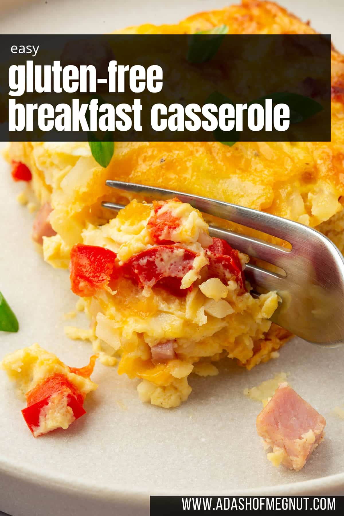 A close up of a fork cutting into a slice of breakfast casserole with ham and red bell pepper.
