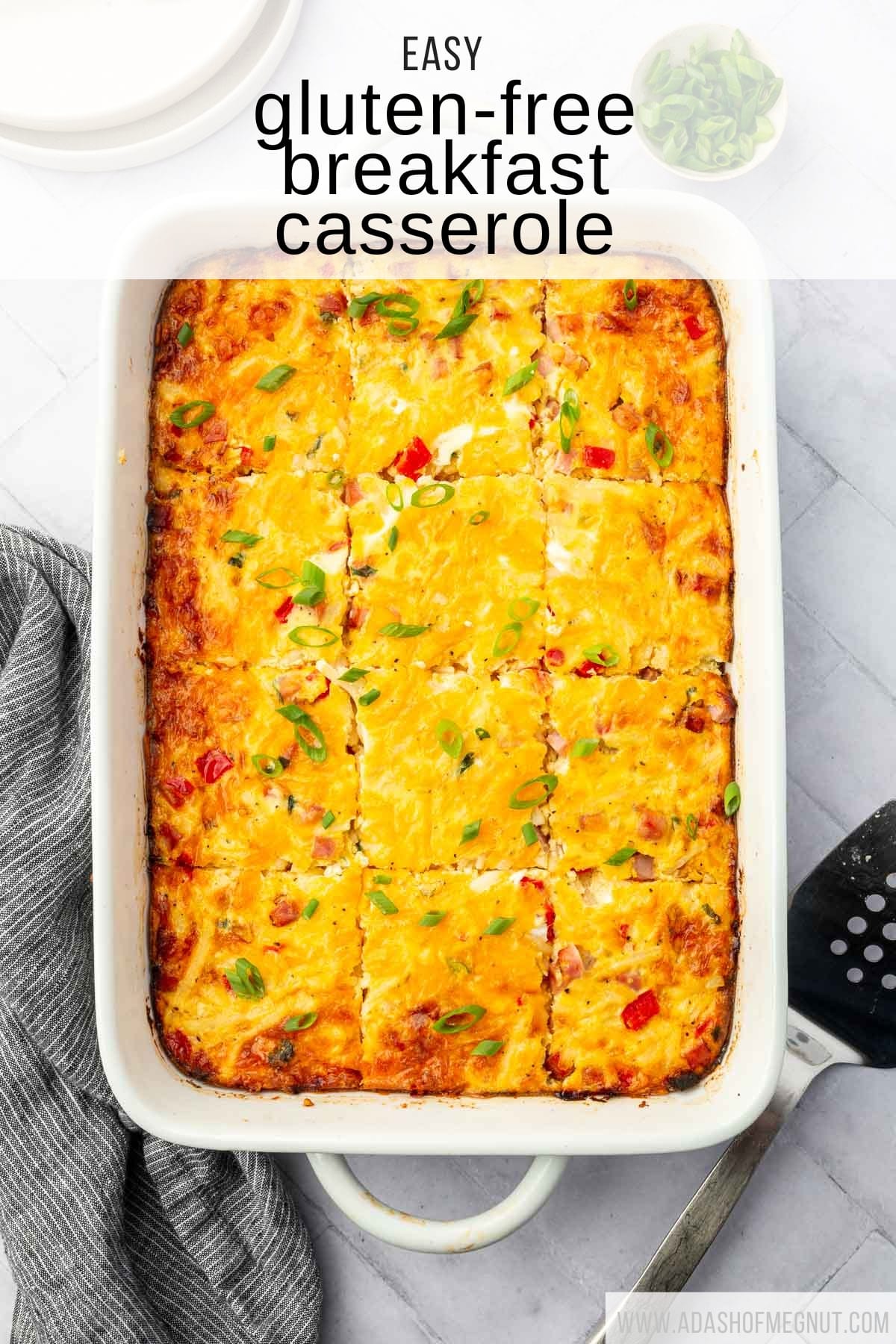 An overhead view of a casserole dish filled with gf breakfast casserole topped with green onions and a spatula to the side.