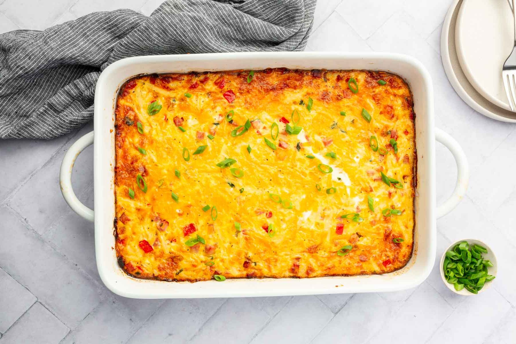 An overhead view of a 9x13-inch baking dish filled with a gluten free breakfast casserole topped with green onions.