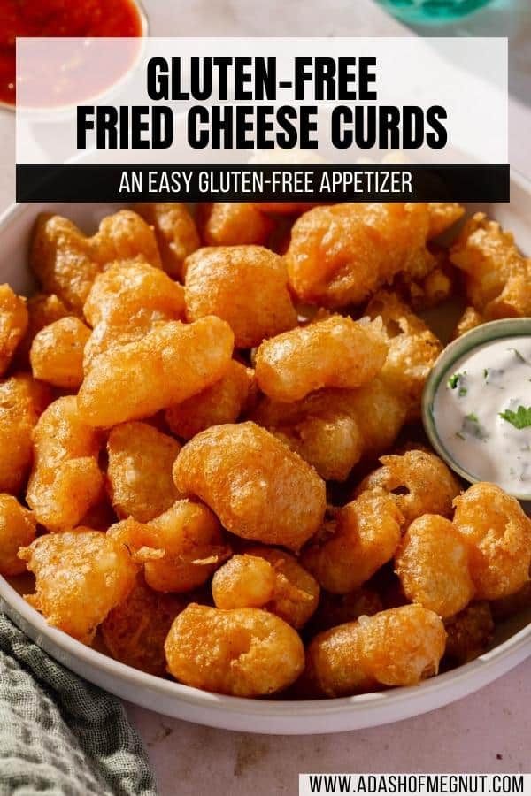 A closeup of a bowl of fried cheese curds with a small ramekin of cilantro ranch on the side.