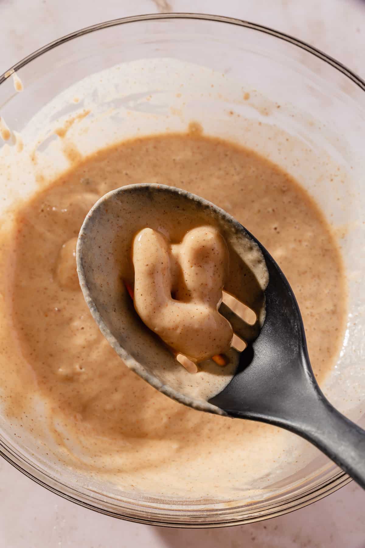 A slotted spoon removing a few cheese curds from the gluten-free batter.