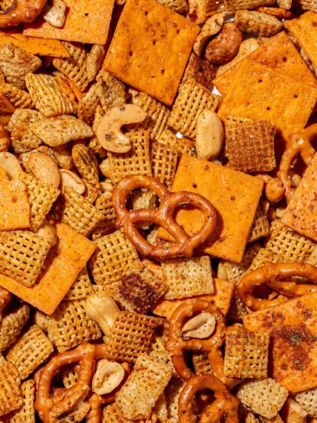 An overhead view of gluten-free chex mix with gluten-free pretzels, cheese cracks, corn chex, rice chex, cashews, and peanuts in it.