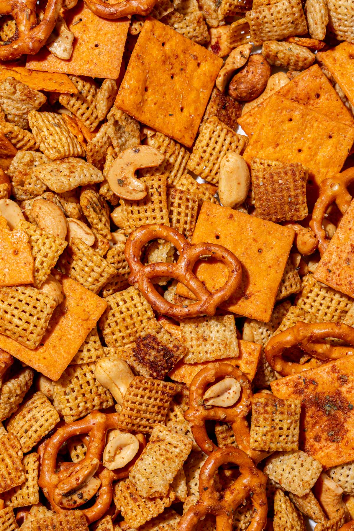 An overhead view of gluten-free chex mix with gluten-free pretzels, cheese cracks, corn chex, rice chex, cashews, and peanuts in it.