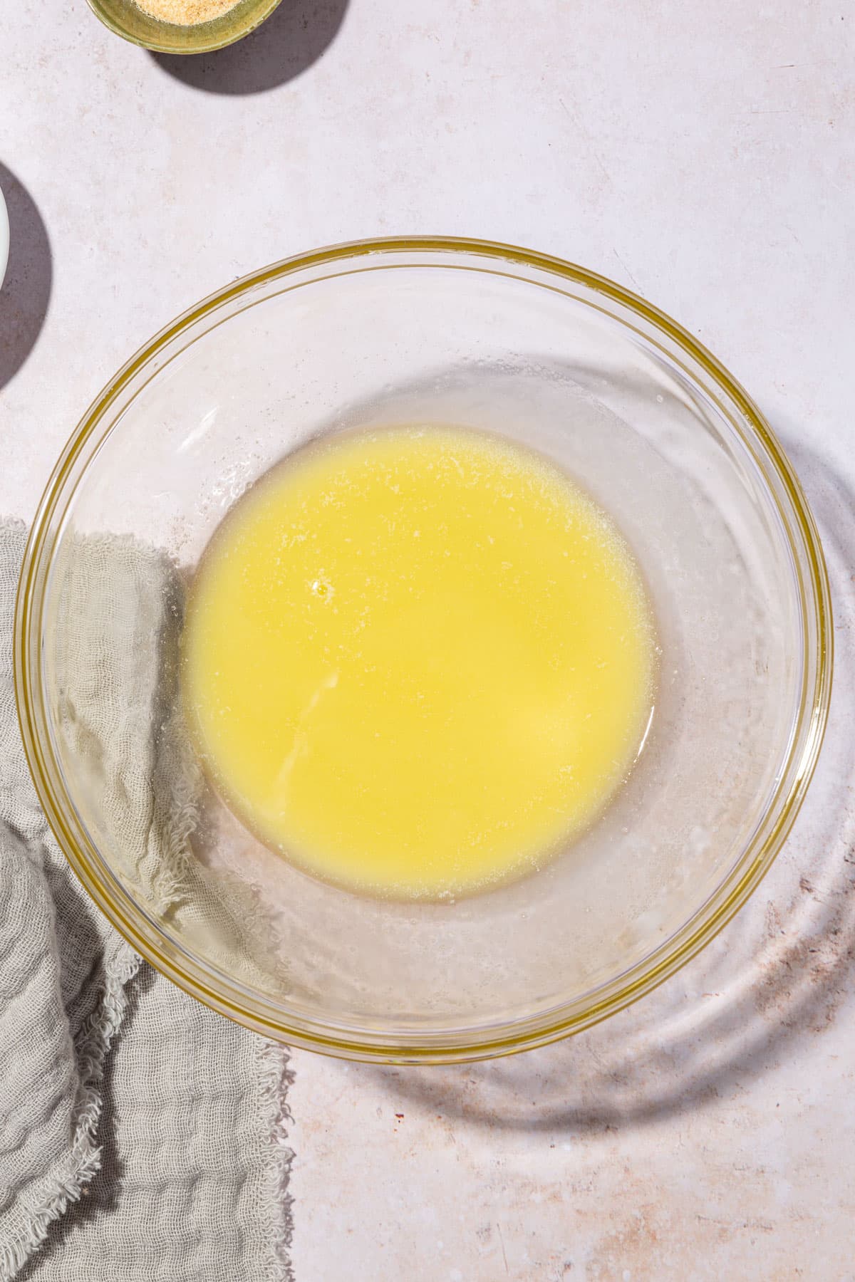 A glass mixing bowl with melted butter in it.