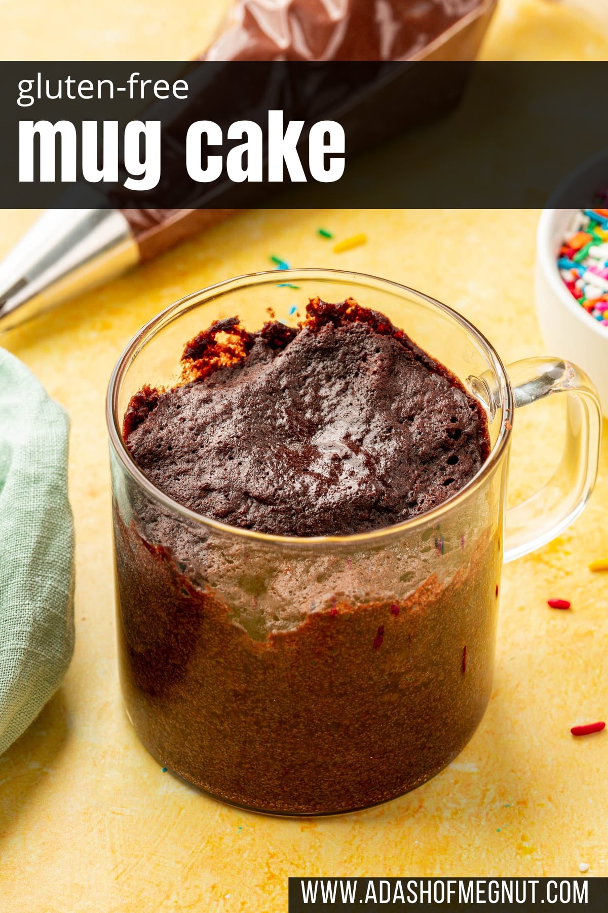 A glass mug of gluten-free chocolate mug cake with a piping bag of chocolate buttercream in the background.