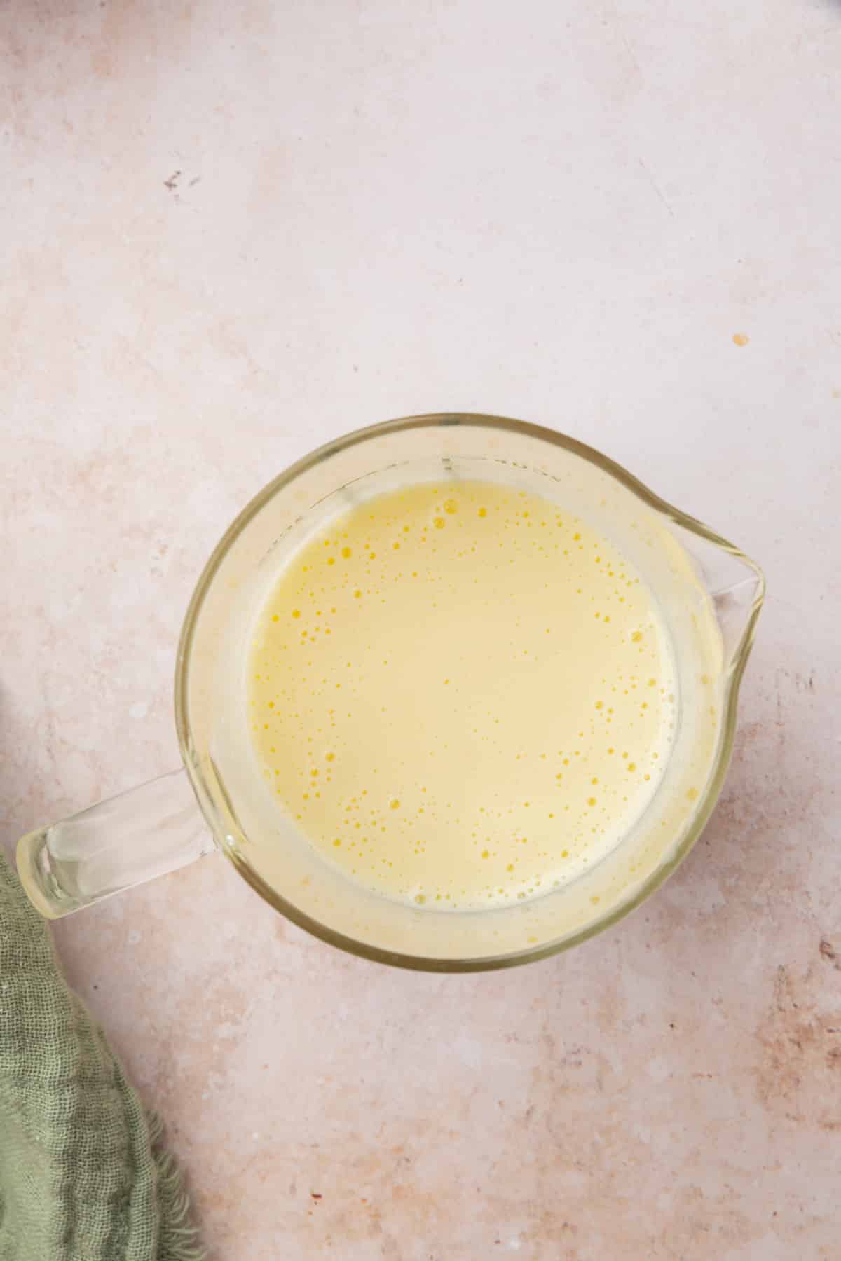 A glass measuring cup with a buttermilk and egg mixture in it.