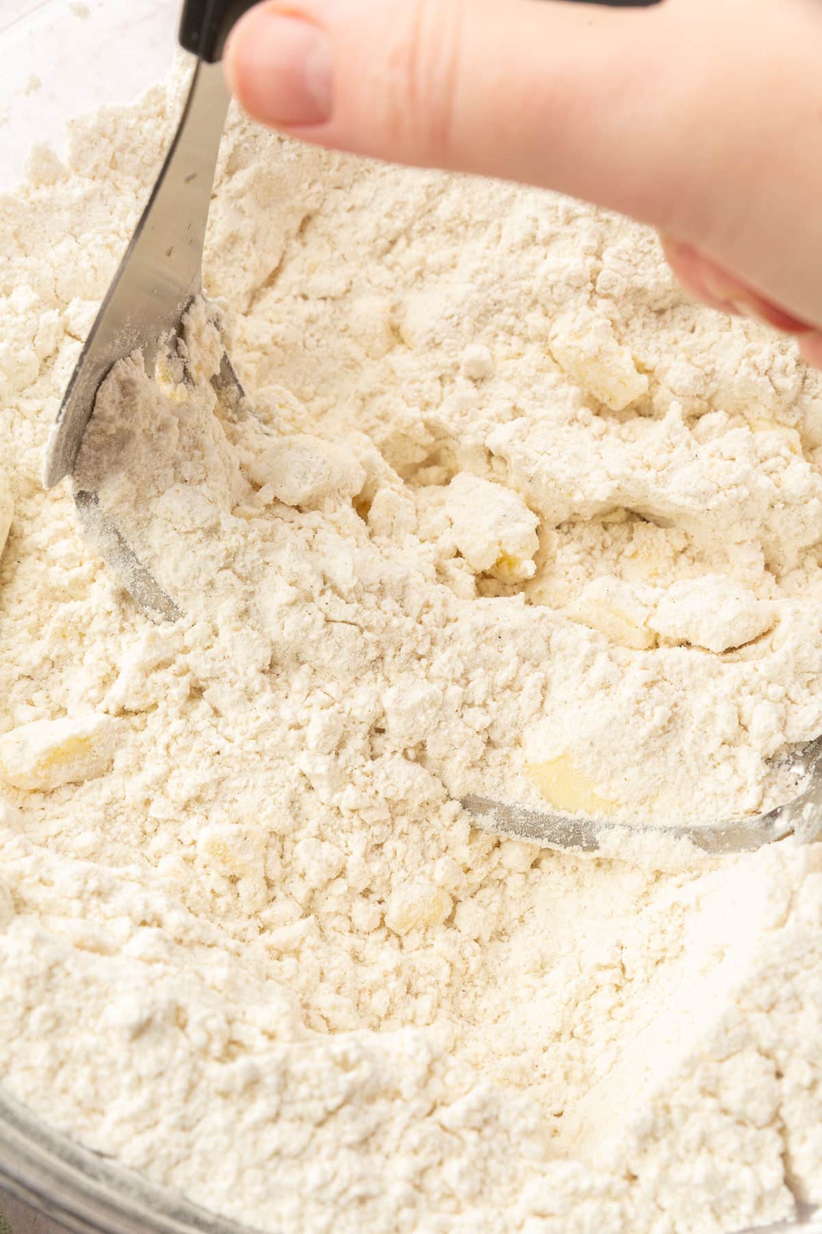 A pastry cutter that is cutting cold butter into a gluten-free flour mixture.