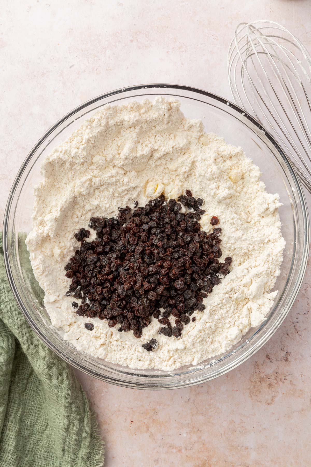 A glass mixing bowl with a gluten-free flour blend mixture topped with currants.