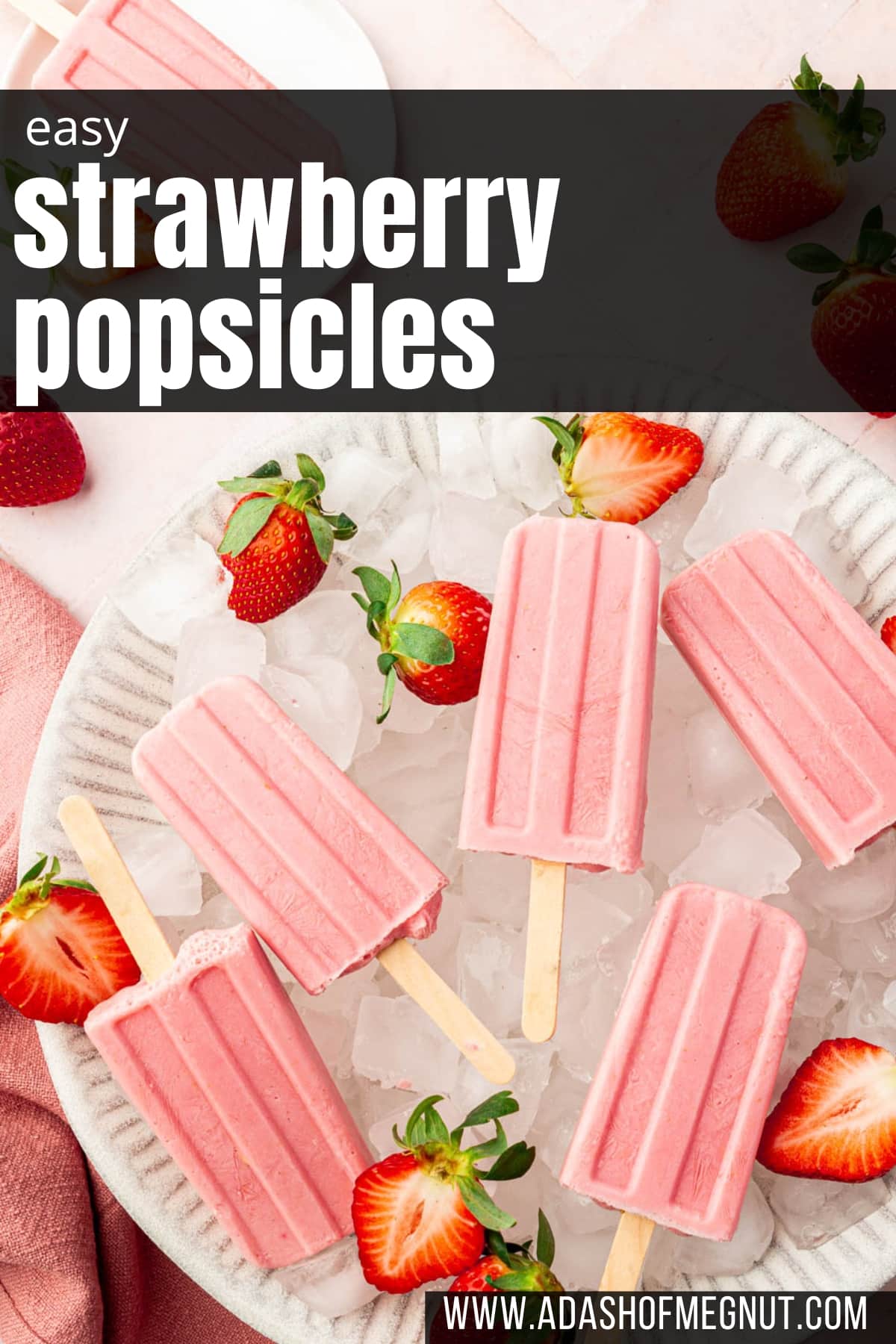 A large bowl filled with ice cubes and topped with strawberry yogurt popsicles with fresh strawberry halves surrounding the popsicles.