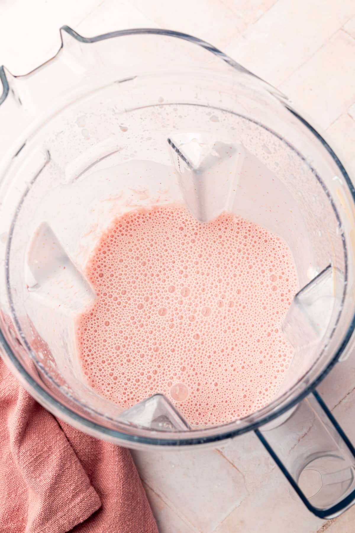 A large blender with a blended strawberry Greek yogurt mixture.