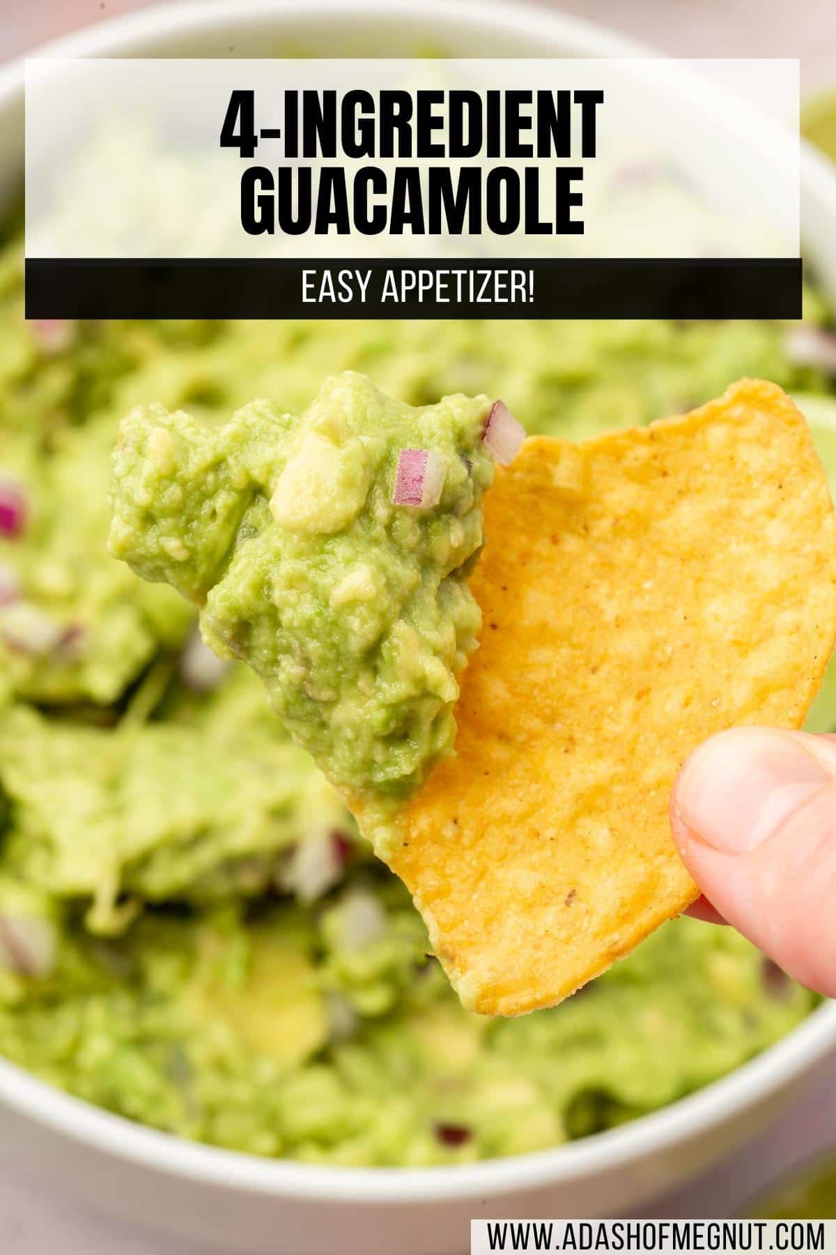 A hand holding a tortilla chip topped with guacamole.
