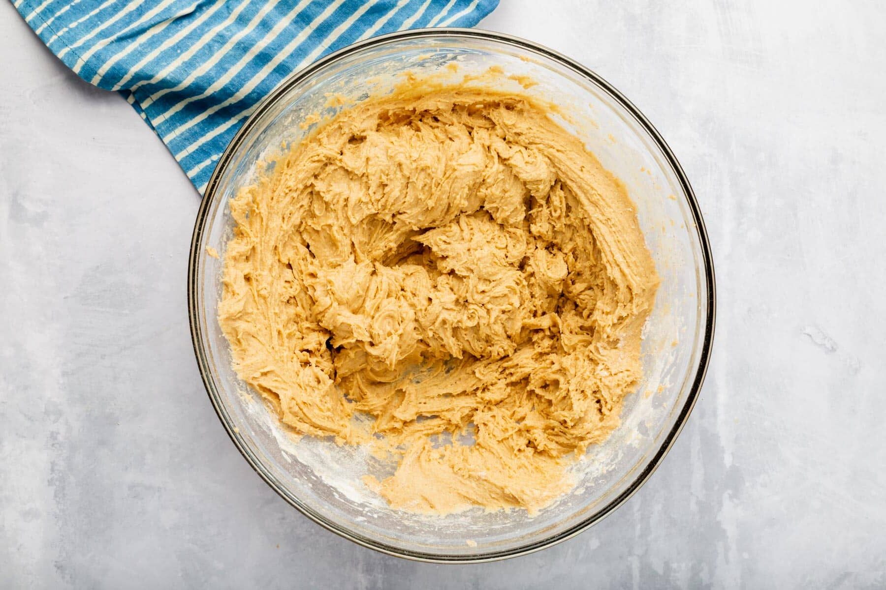A glass mixing bowl with gluten free cookie dough batter in it.