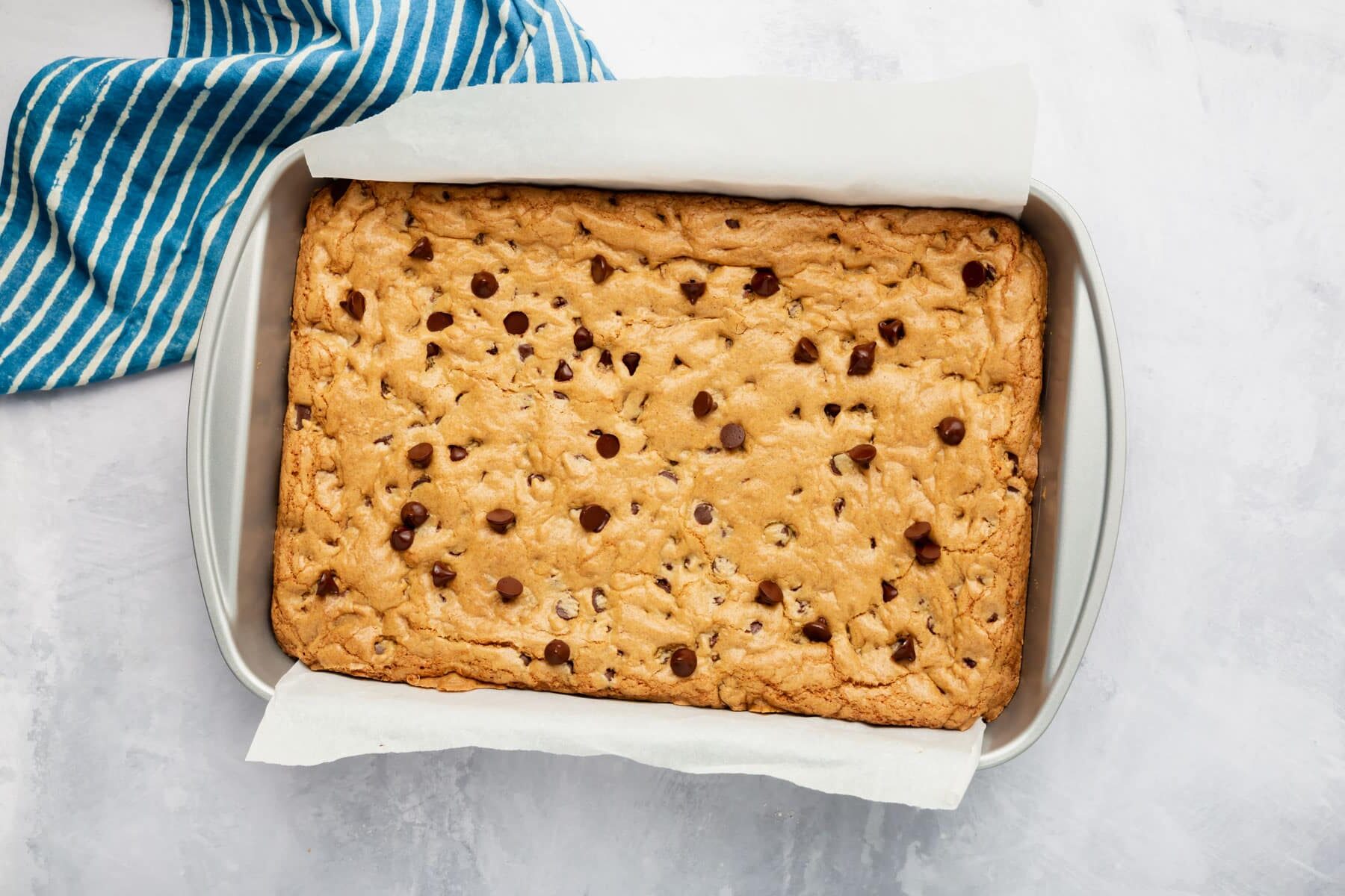 A rectangle metal baking pan with baked gluten-free chocolate chip cookie bars in it.