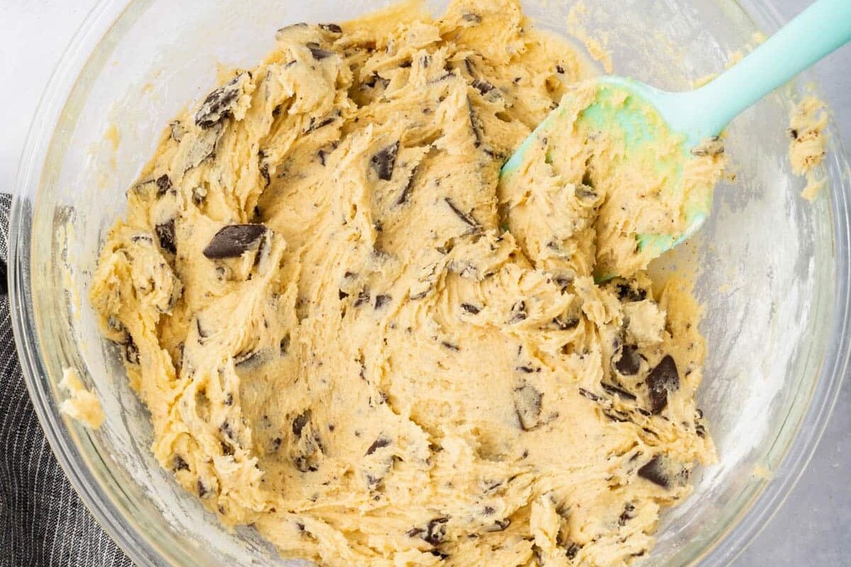 A glass mixing bowl with gluten-free chocolate chip cookie dough in it.