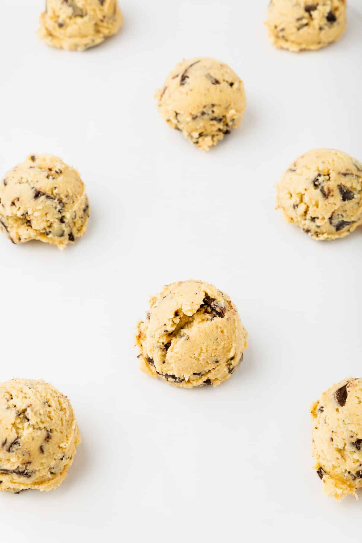 Gluten-free chocolate chip cookie dough balls on parchment paper.