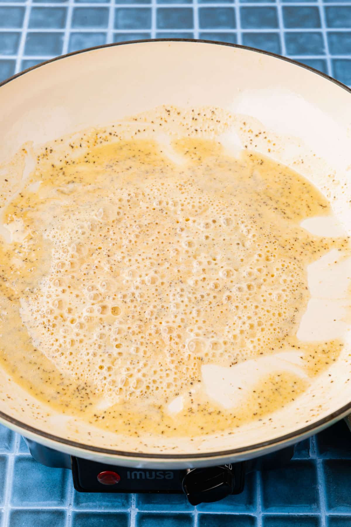 A gluten free roux in a white pan that is bubbling up and golden brown.