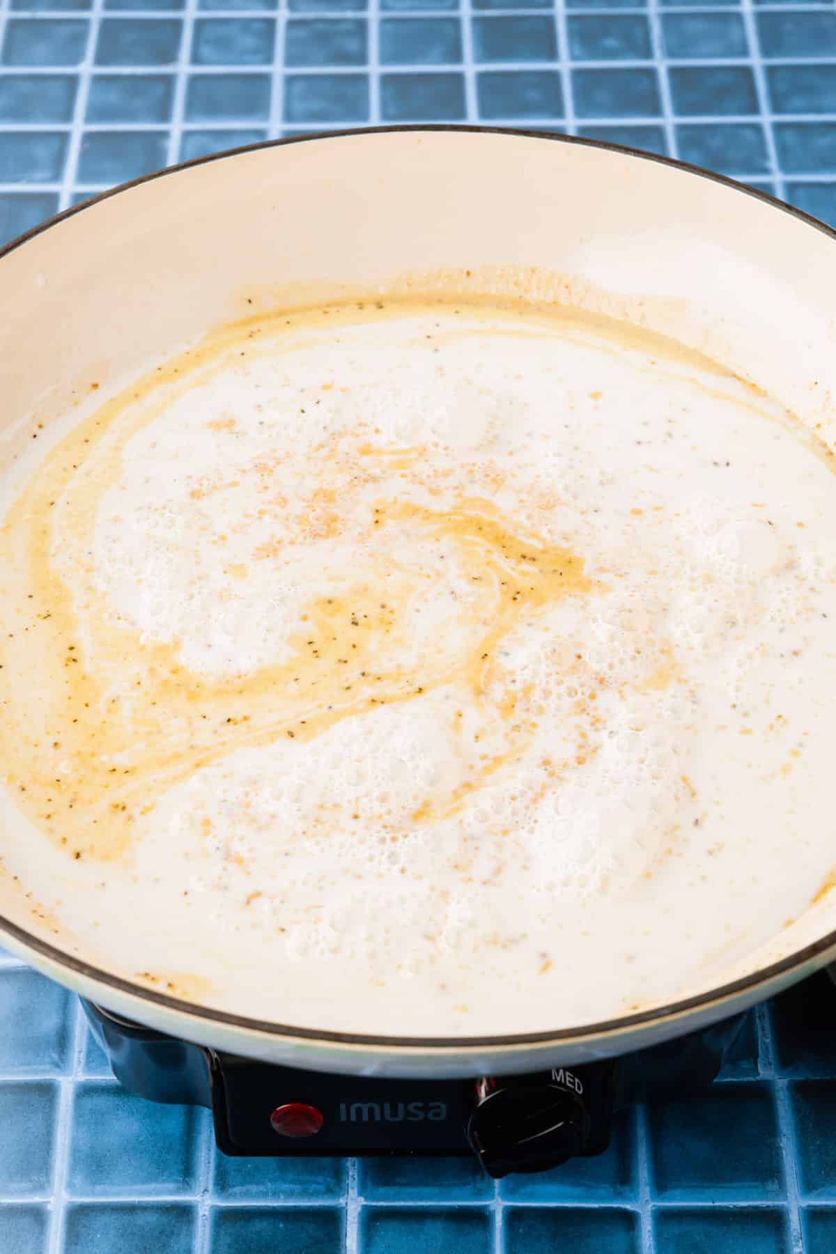 A white braising pan with a milk and gluten free roux to make a creamy sauce.