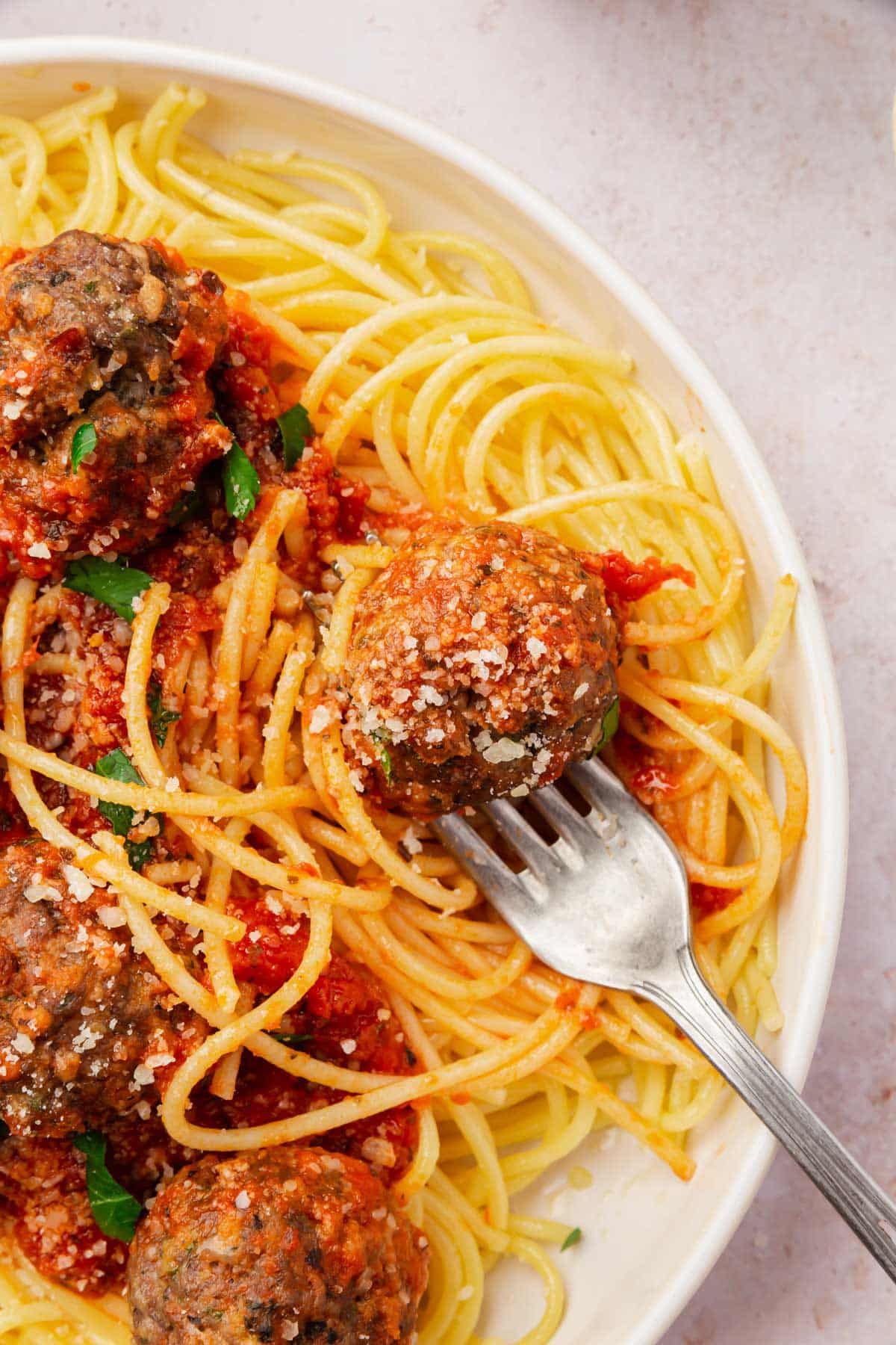 A bowl of spaghetti, gluten-free meatballs and marinara sauce with a fork.