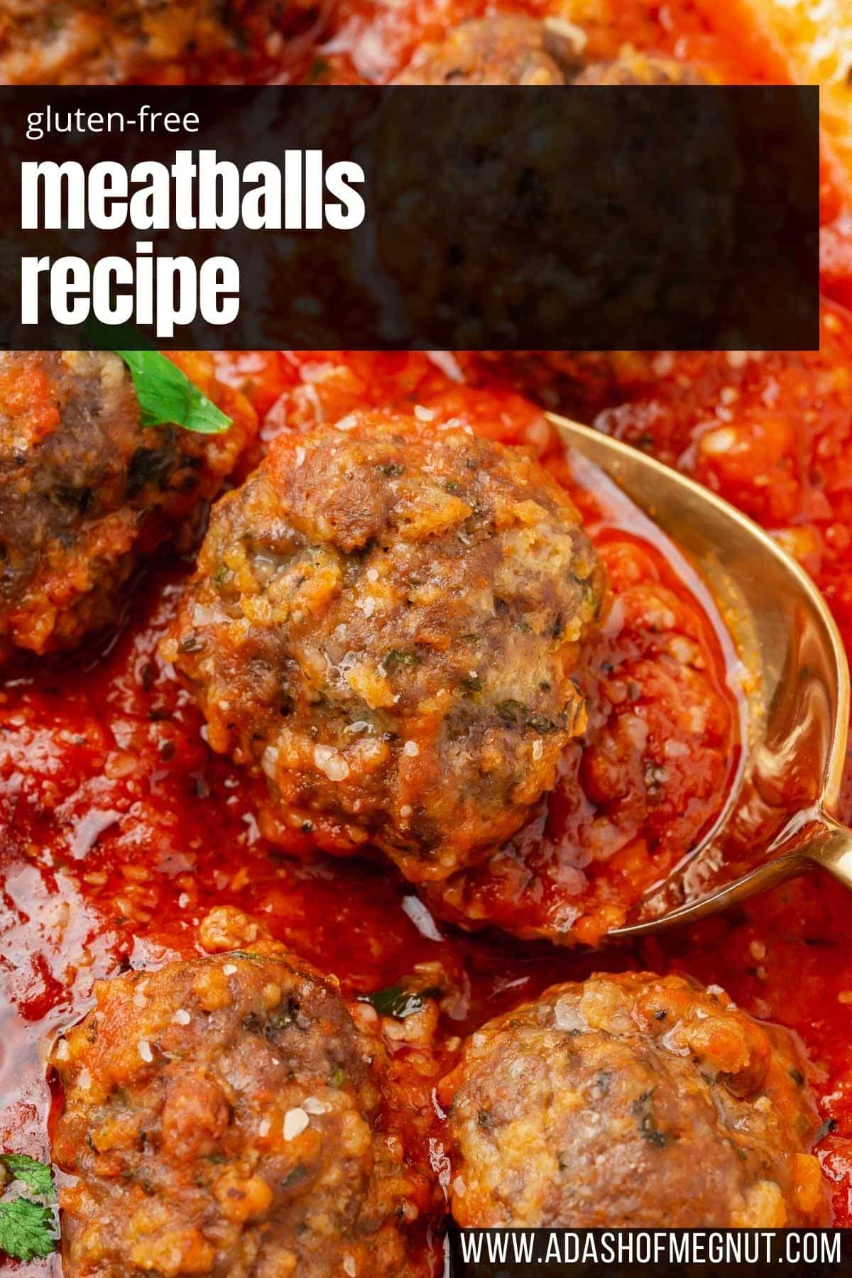 A closeup of gluten-free meatballs simmering in marinara sauce with a spoon under one beef meatball.
