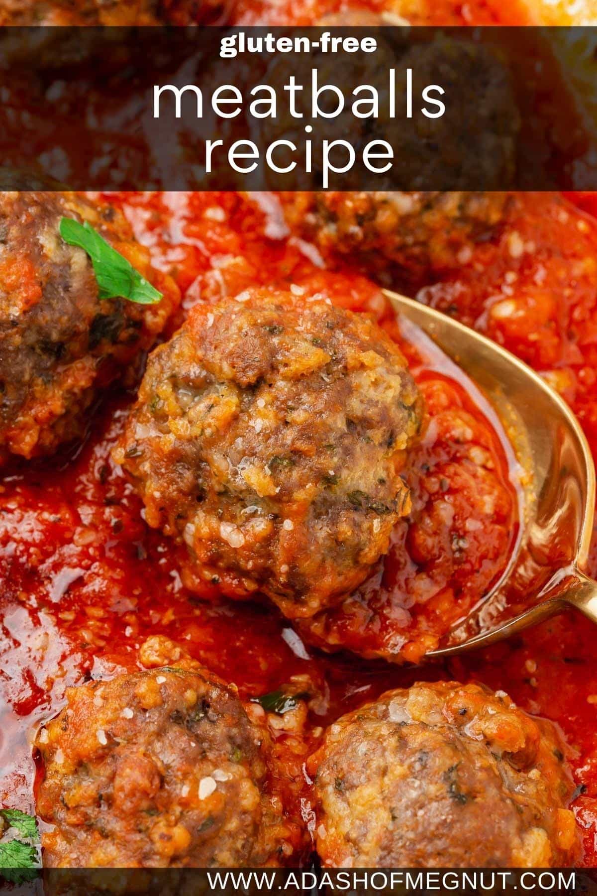 A closeup of gluten-free meatballs simmering in marinara sauce with a spoon under one meatball.