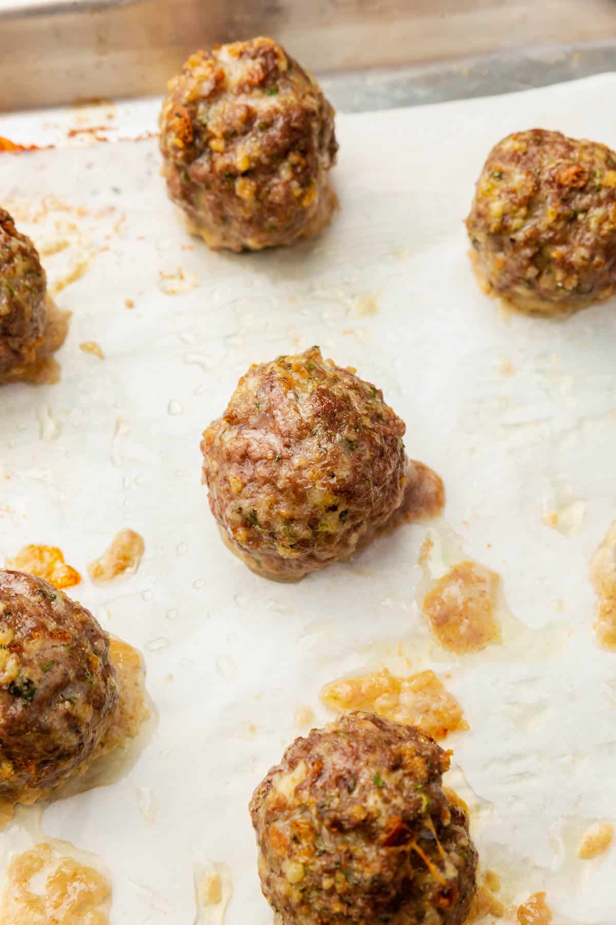 Cooked gluten-free meatballs on a sheet pan lined with parchment paper.