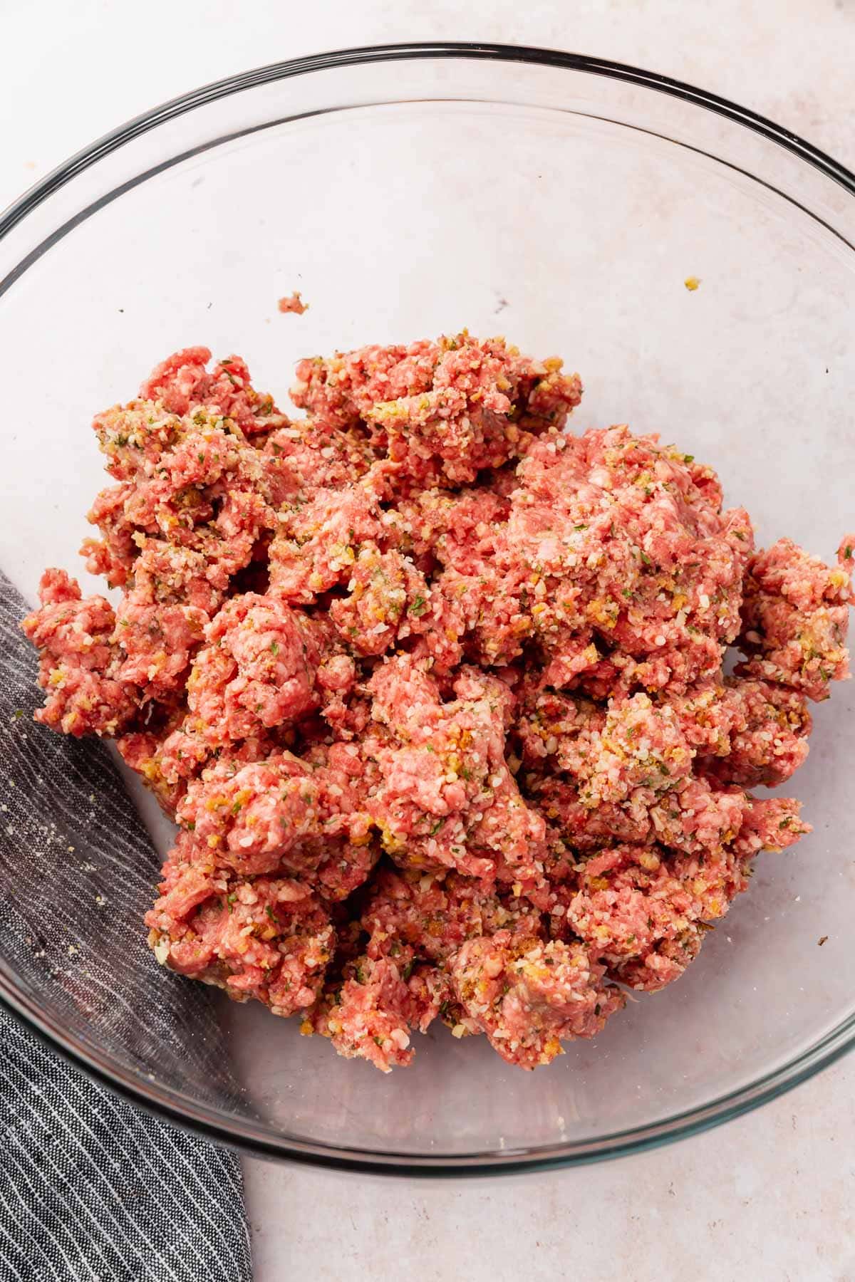 A bowl of ground beef mixed with spices, parmesan and gluten-free breadcrumbs to make meatballs.