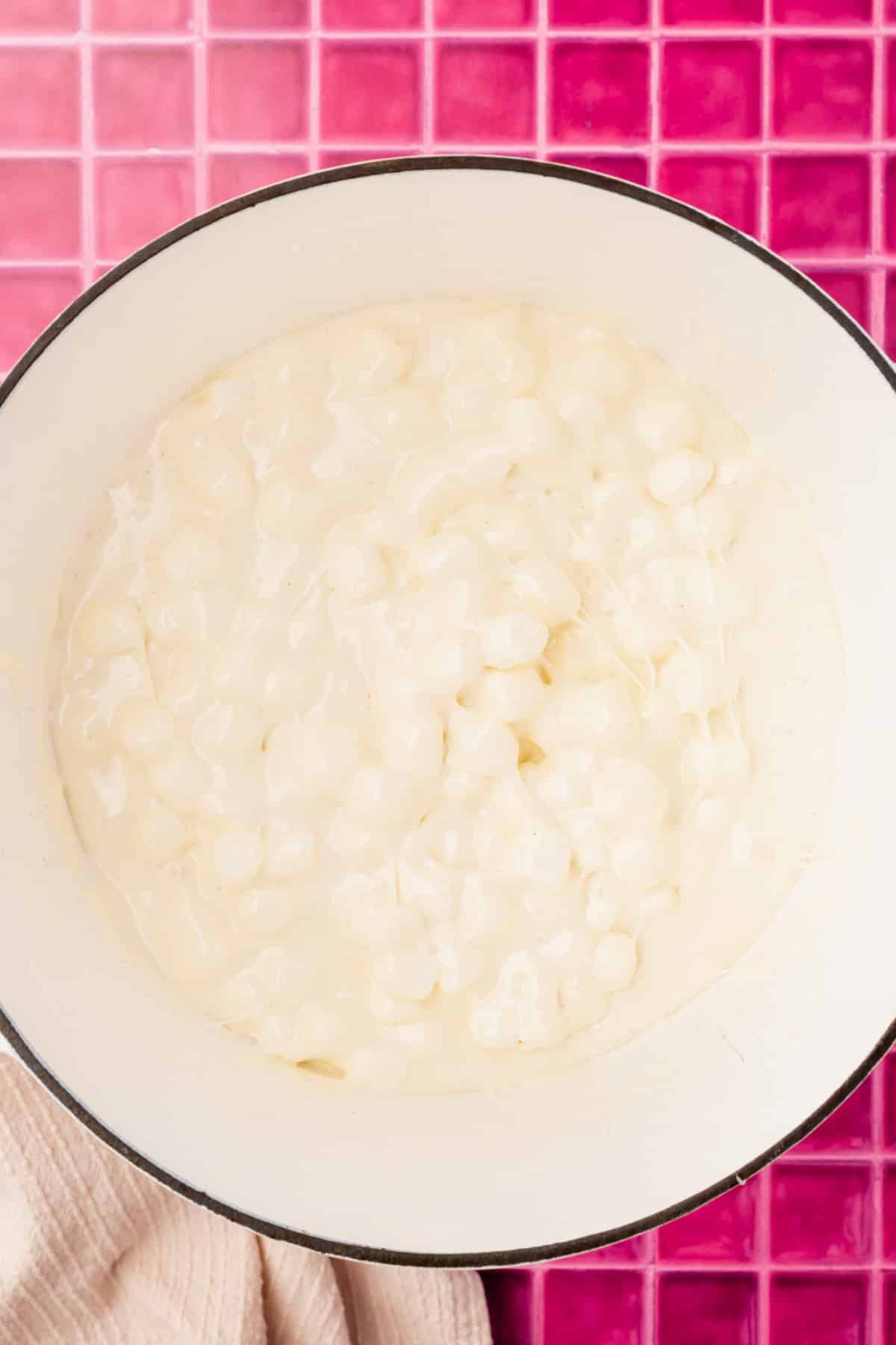A white dutch oven filled with semi-melted marshmallows.