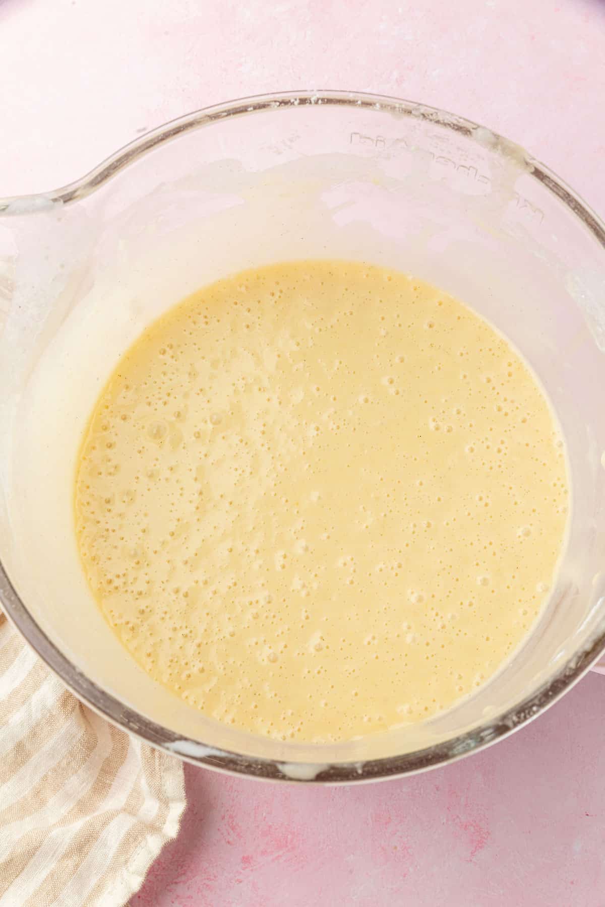 A glass mixing bowl with gluten free cake batter in it.