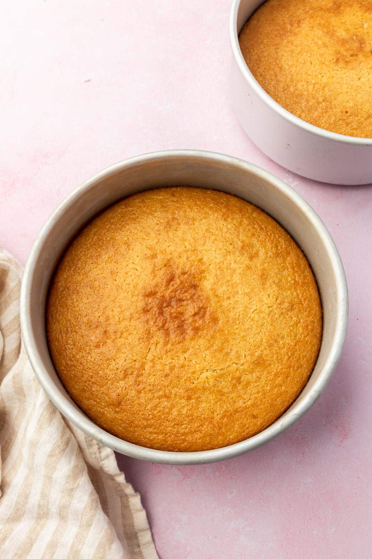 Two round 8-inch baking pans with gluten-free vanilla cake in them after baking in the oven.