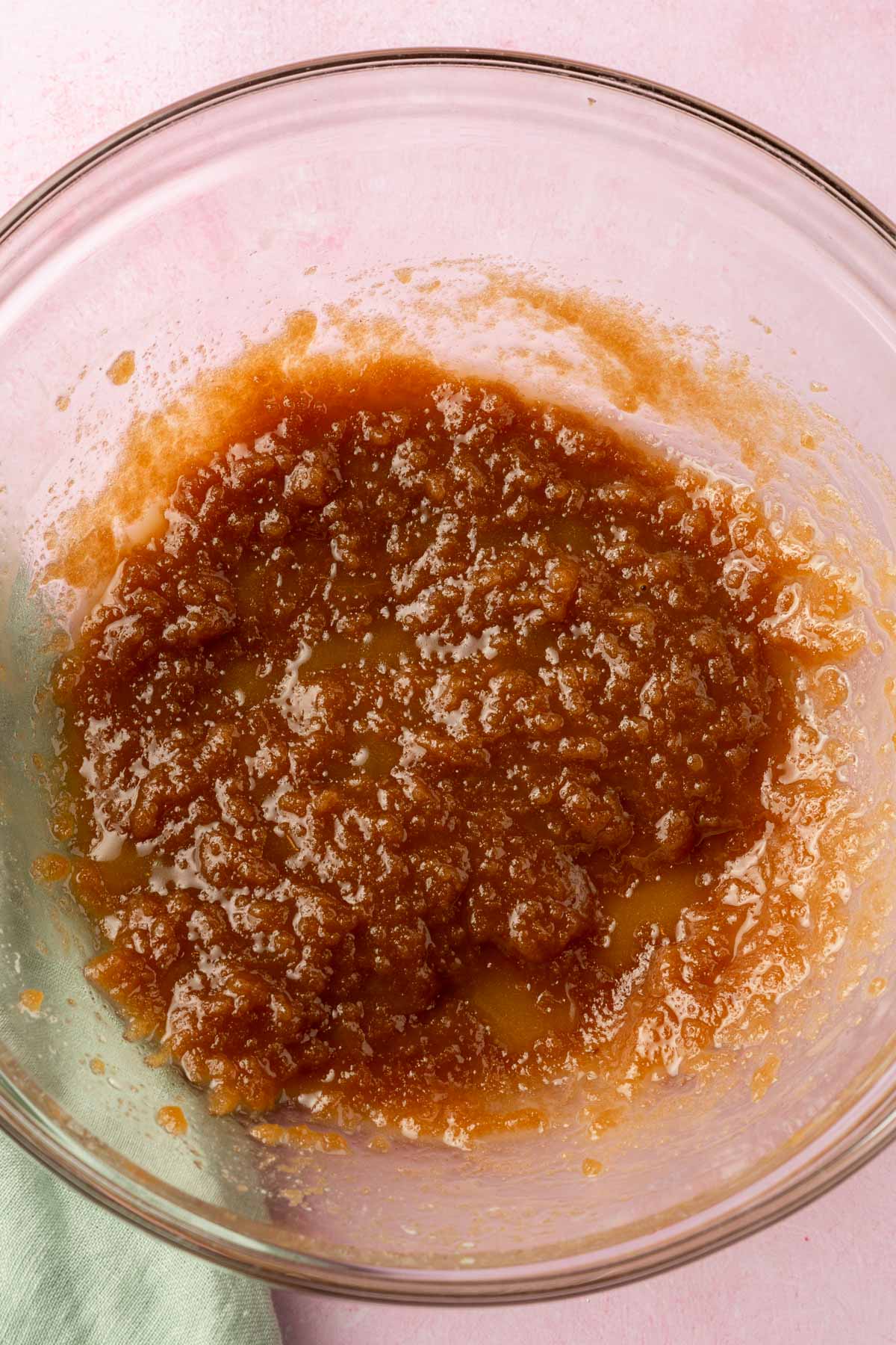 A glass mixing bowl with a brown sugar and melted butter mixture in it.
