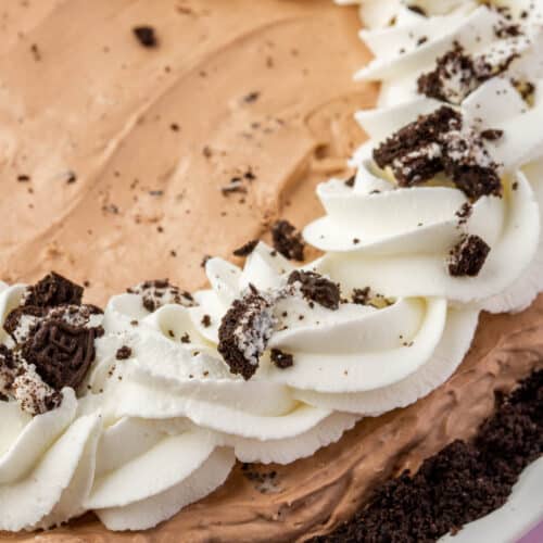 A closeup of a full gluten free Oreo mud pie topped with whipped cream swirls and crushed gluten-free Oreos.