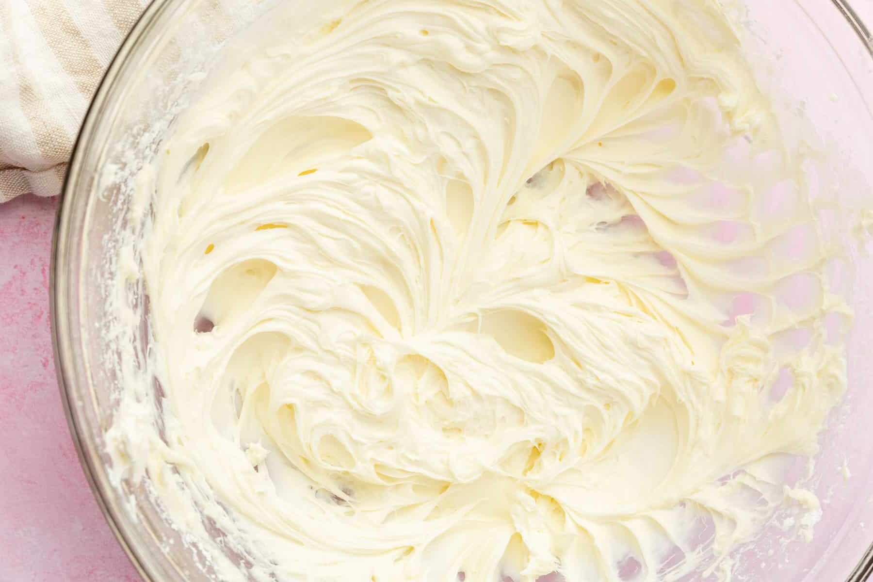 A glass mixing bowl with whipped cream cheese in it.