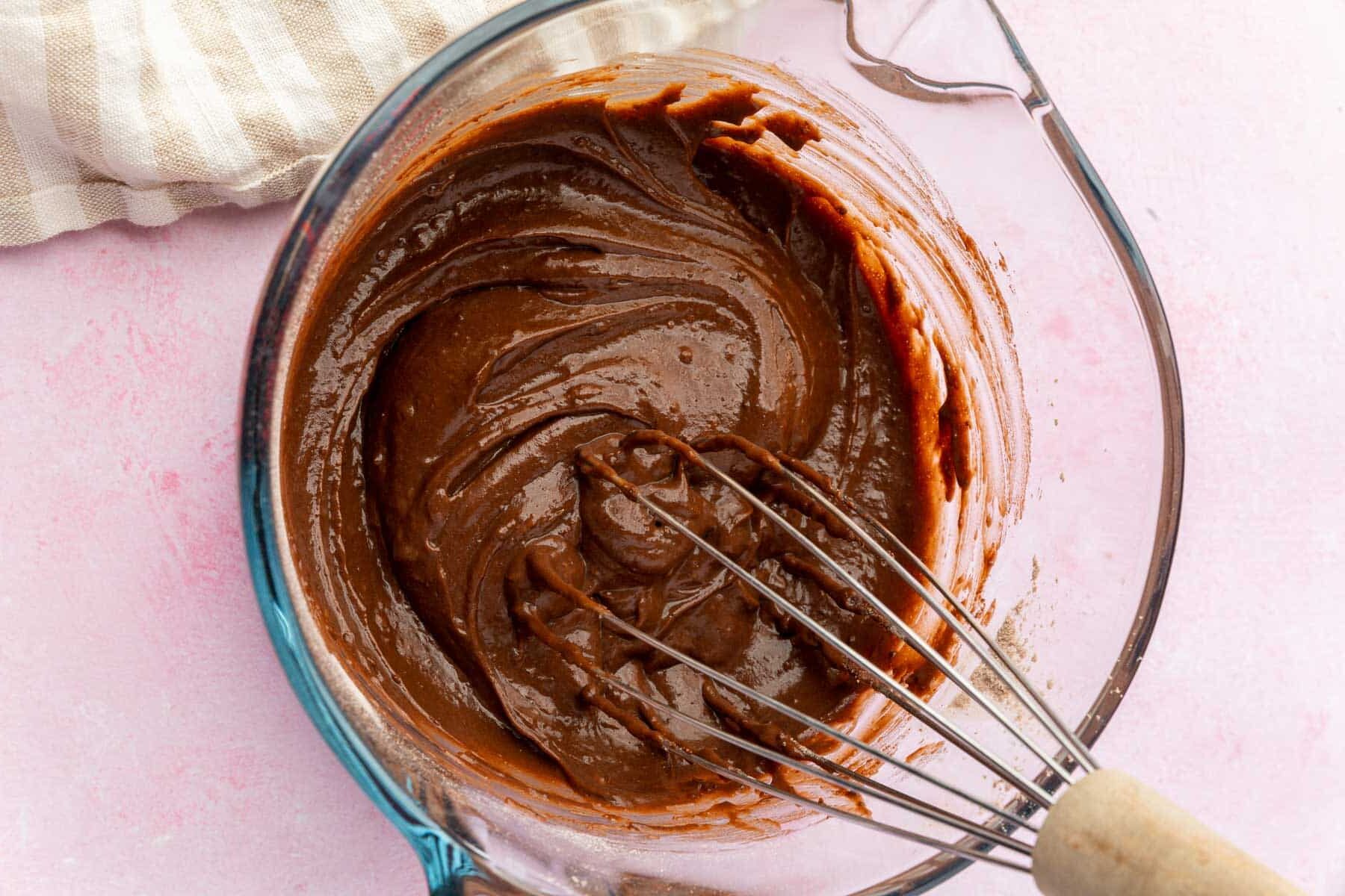 Chocolate pudding in a measuring glass with a whisk.