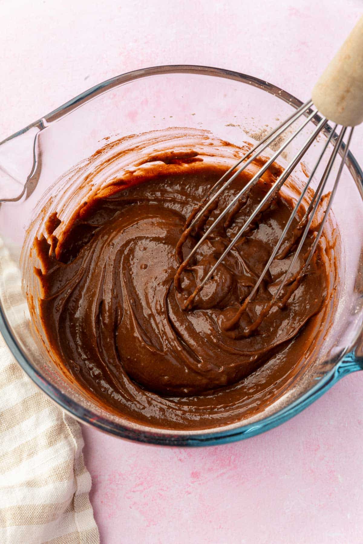 Chocolate pudding in a measuring glass with a whisk.